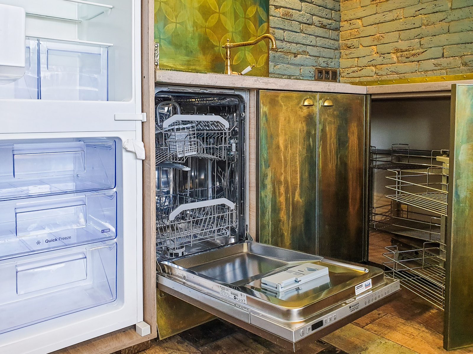 Open built-in dishwasher in a kitchen with brass cabinet doors