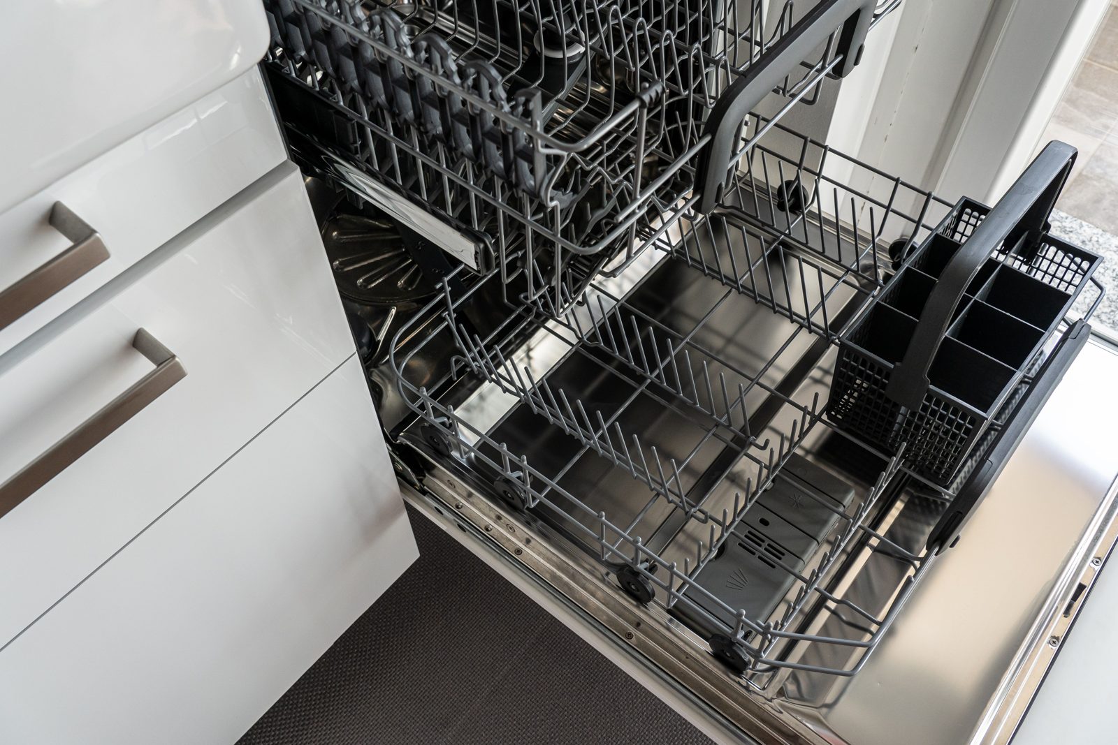 Overhead view of dishwasher upper and lower racks with a removable cutlery basket