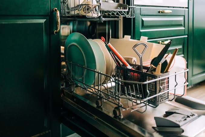 Loaded dishwasher lower rack with plates and a utensil basket